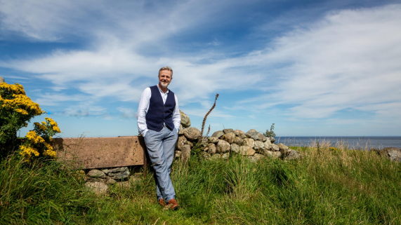 Michael Londra standing in front of stone wall in Ireland