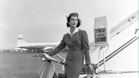 Historic photo of female flight attendant standing in front of a plane