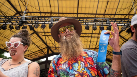 pie eating contestant holding up blue ribbon