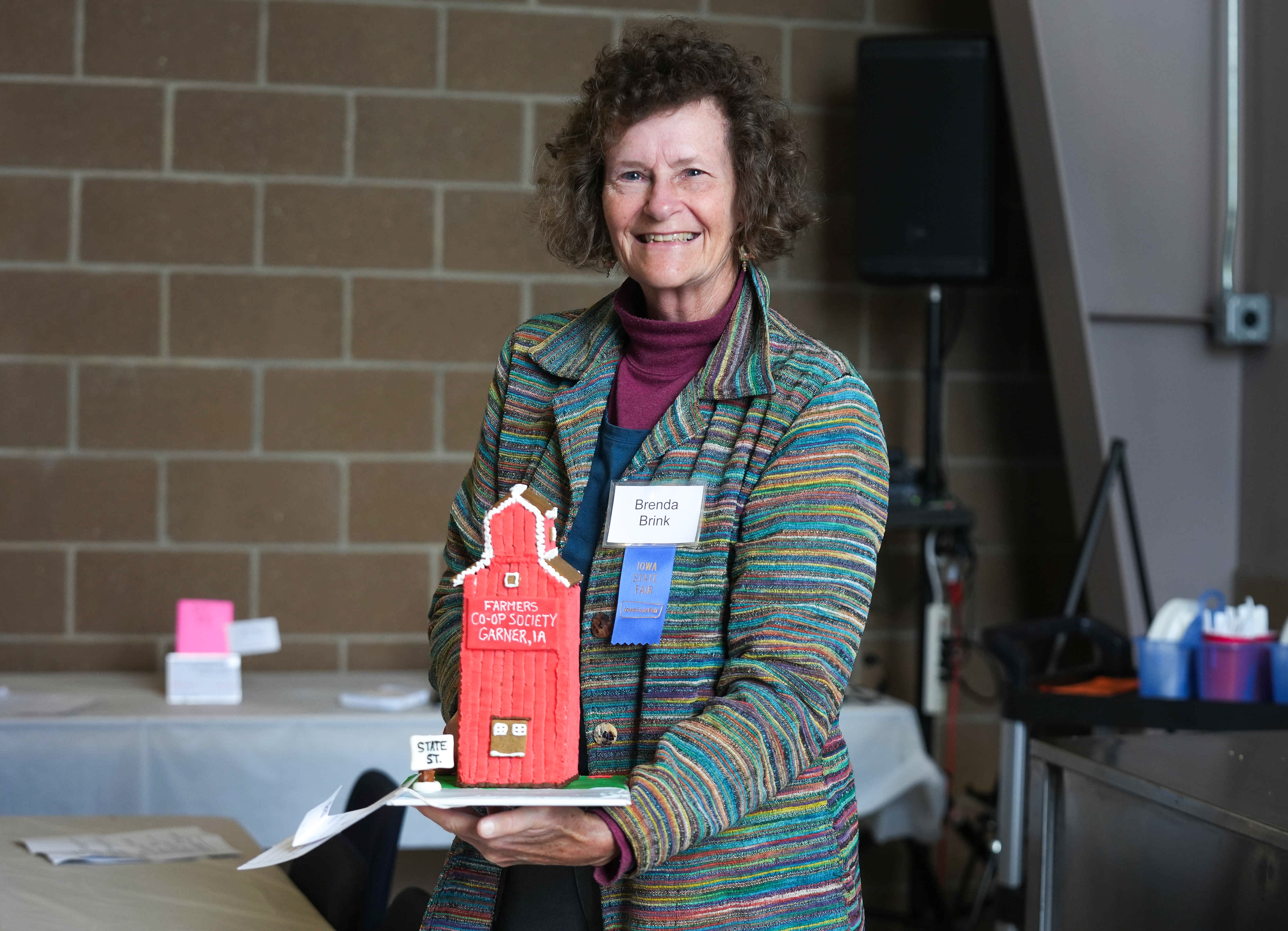 Gingerbread judge Brenda Brink holds a gingerbread grain elevator