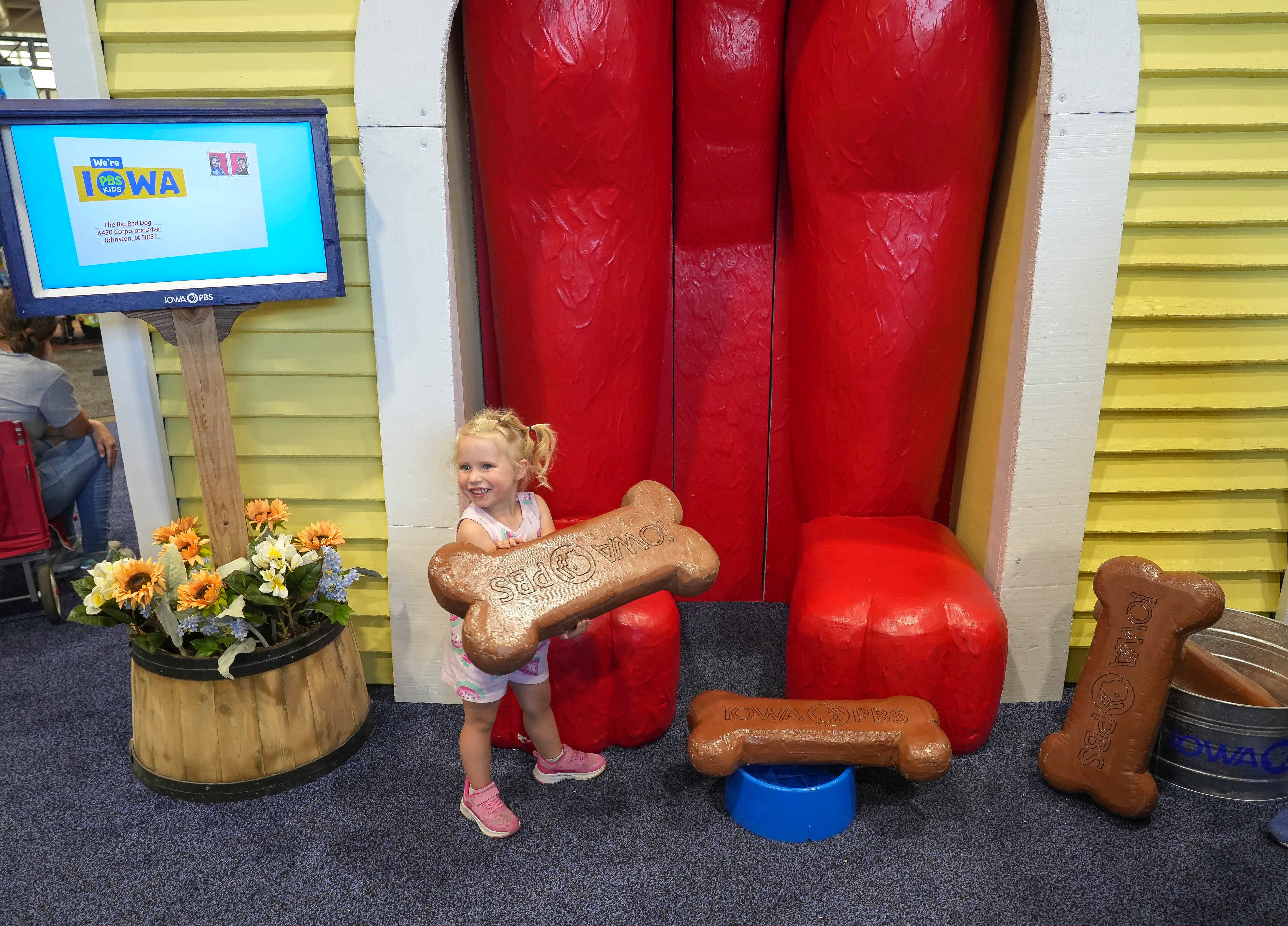 Little girl posing at the Iowa PBS Booth with a life-size Clifford