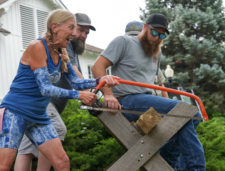 Timber Sports lady sawing with men holding things in place