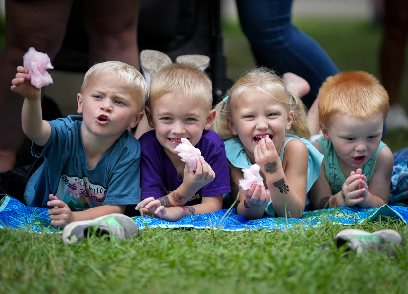 Children snack on state fair cotton candy while laying out on the lawn of Pioneer Hall