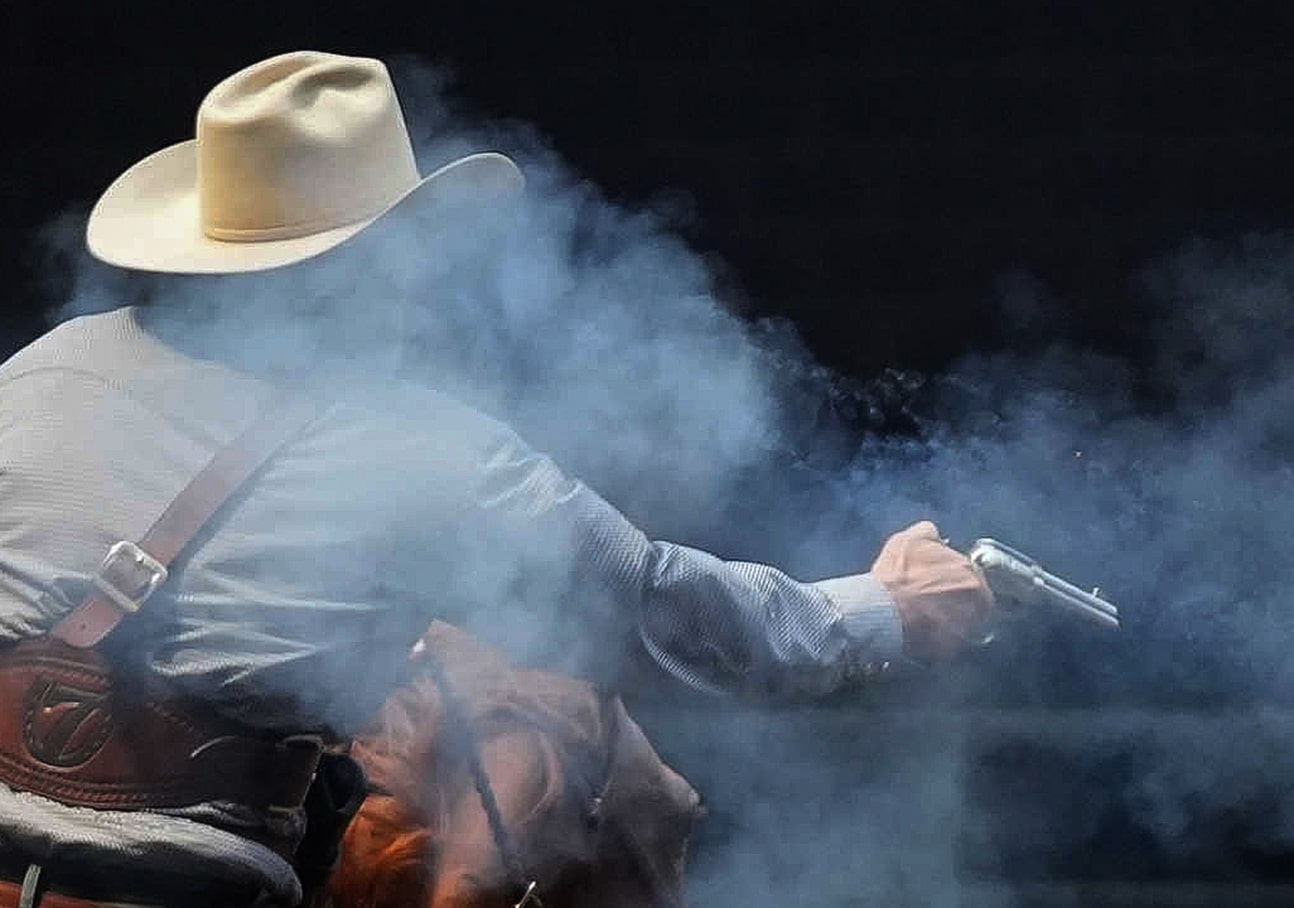 Smoky picture of a cowboy shooting a gun on horseback. 