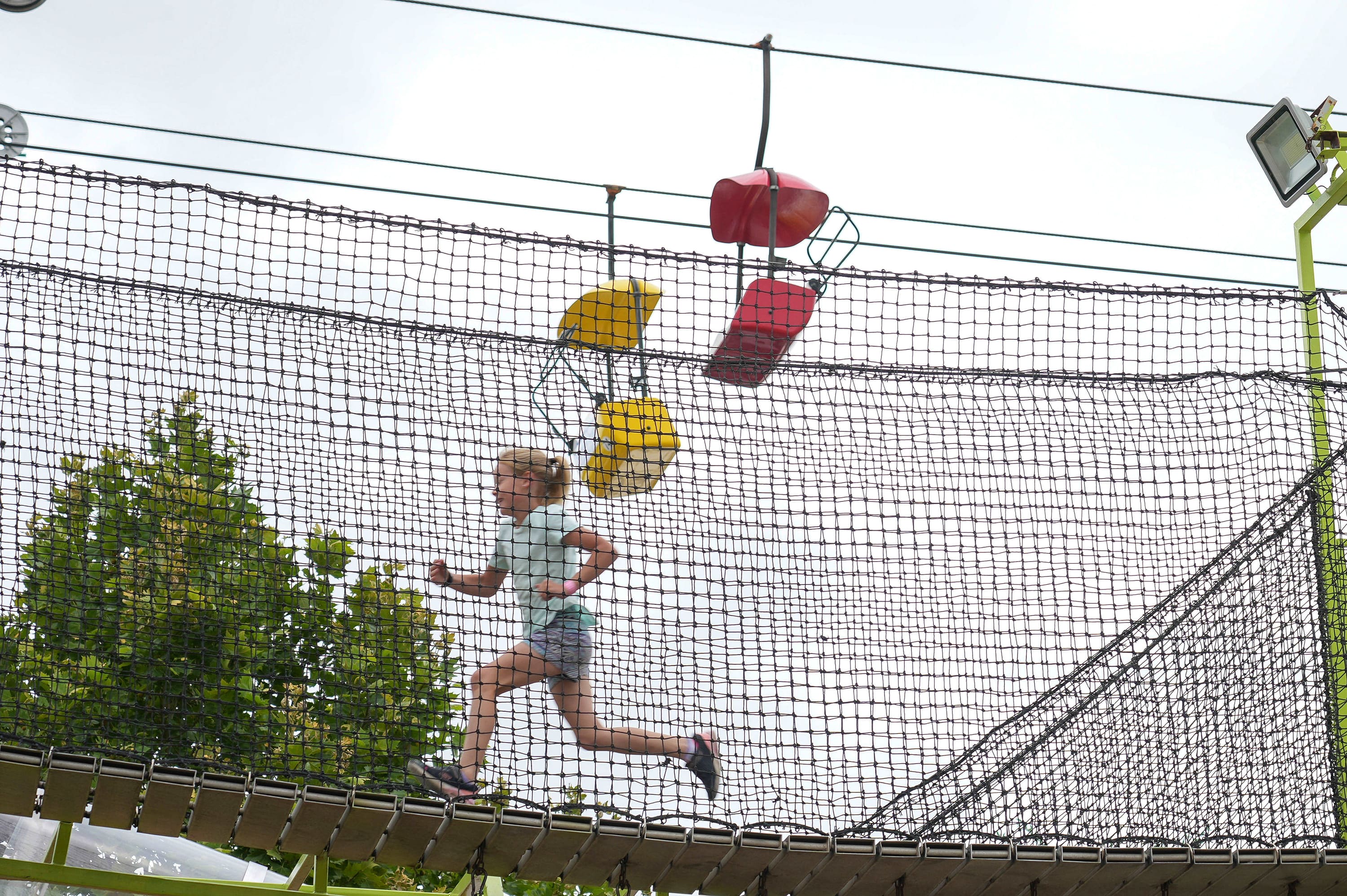 A child playing at the fairgrounds with the skyglider visible behind them.