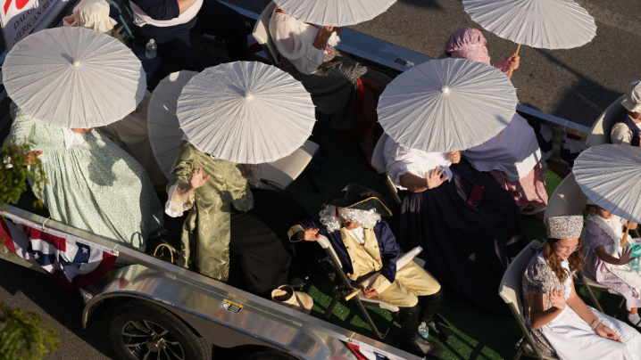 Revolutionary cosplayers get some shade under umbrellas while cruising on their floats.