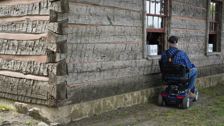 Man in a scooter listening to hymn music outside an old church