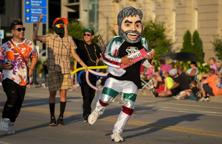 Man with large mask and musical instrument in the Iowa State Fair parade