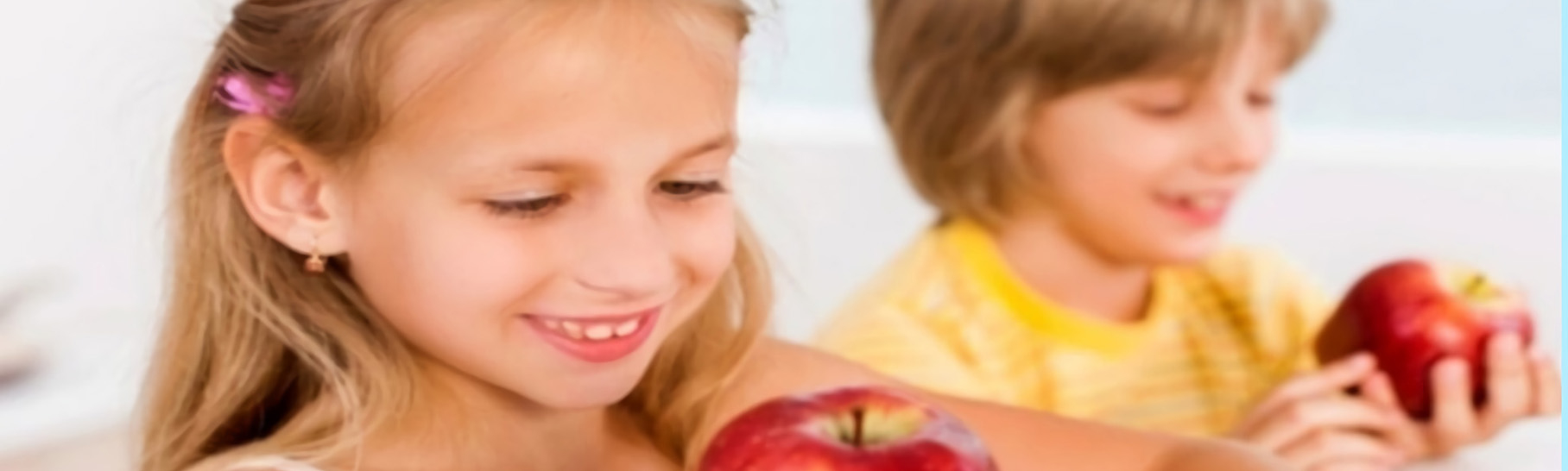 A young girl and boy holding apples.