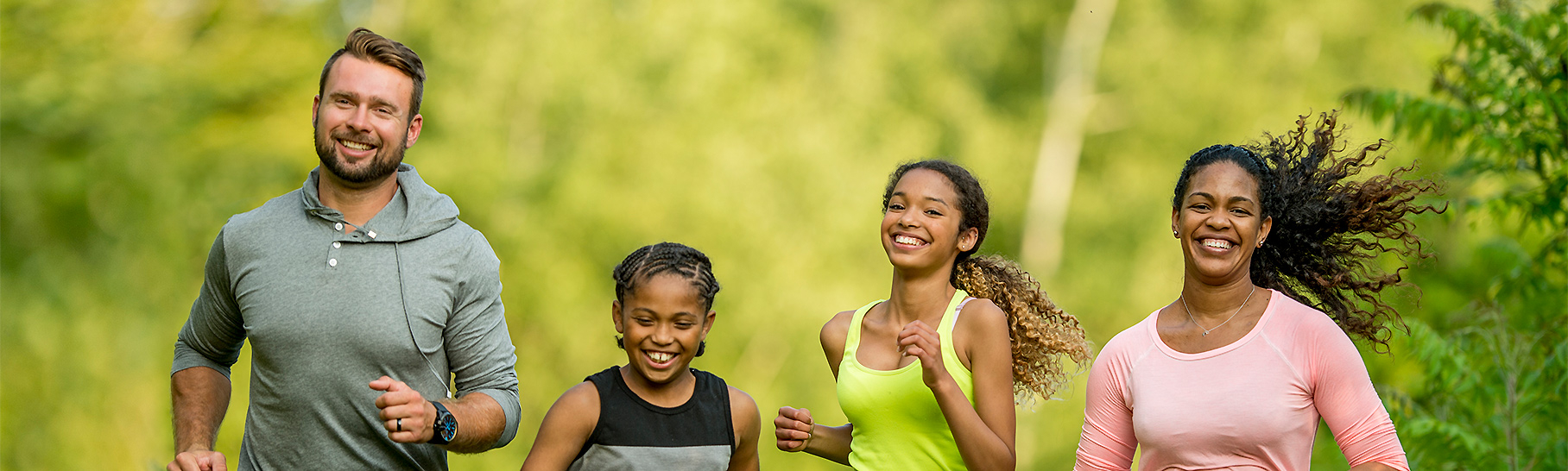 A family of four running outdoors.