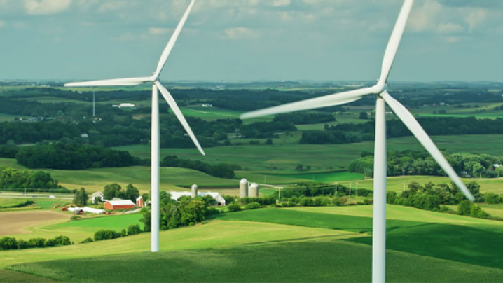 two industrial windmills in a farm field. 