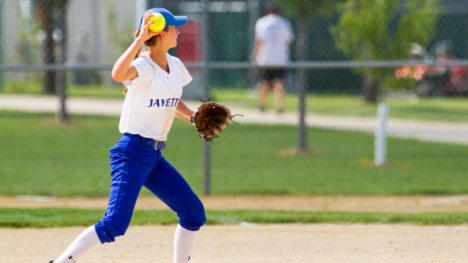 A high school girl throwing a softball