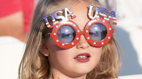 Photo of young girl wearing patriotic sunglasses that say "USA" on top 