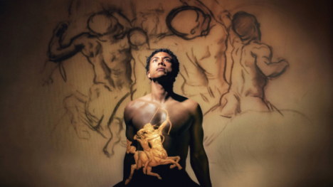 A black man looking up with the Apollo symbol on his chest