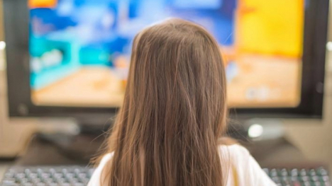 The back of a little girl's head watching TV