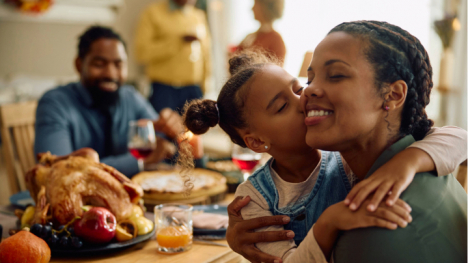 Little girl kissing mom at Thanksgiving dinner