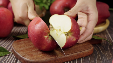 A red apple being sliced in half with a knife