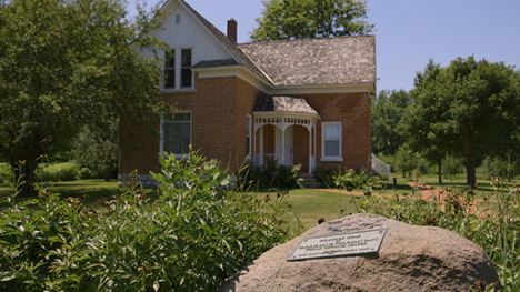 A two story brick house with white accents and a stone foundation.