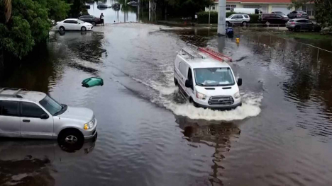 Heavy rains strike Florida - a white van drives through a flooded street.