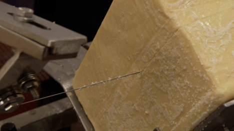 A block of cheese being cut.