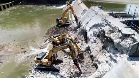 Excavators removing concrete dam