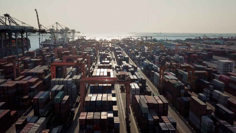 Stacks of shipping containers in oceanside port.