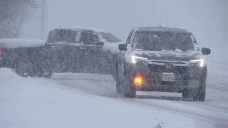 Two trucks on a slippery road during a snowstorm.