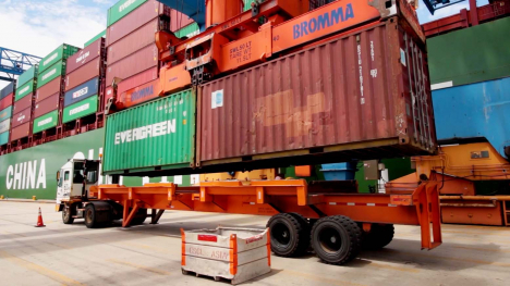 shipping containers being loaded onto a truck in a port facility